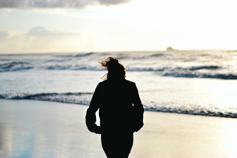 Woman walking on the beach at sunset